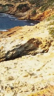 Dalgalar Fransa 'nın Korsika kentindeki Delta du Fango sahilindeki engebeli ve kayalık uçurumlara çarpar. Temiz mavi su ve desenli taş oluşumlarıyla doğal manzara..