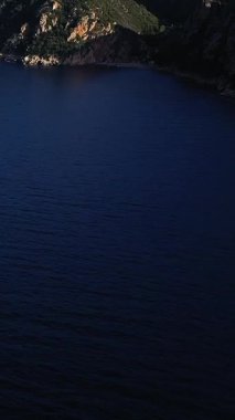 Calanques de Piana, Korsika 'da berrak bir gökyüzünün altında dramatik kayalıklar ve yemyeşil tepeler yükseliyor..