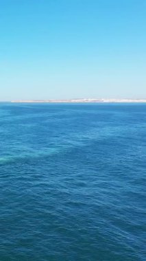 Portekiz 'in Albufeira yakınlarındaki Algarve kıyısında berrak bir gökyüzünün altında derin mavi okyanus manzarası. Güneşli bir günde uzak kıyı şeridi ile sakin deniz manzarası.