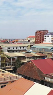 Battambang, Kamboçya 'nın merkezindeki renkli çatıların ve alçak binaların hava manzarası, parçalı bulutlu bir gökyüzünün altında..