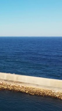 Portekiz, Sagres yakınlarındaki Algarve kıyısında berrak bir gökyüzü altında taş ve beton bir deniz bulunan sakin mavi okyanus..