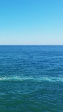 Portekiz 'in Albufeira yakınlarındaki Algarve kıyısı boyunca açık bir gökyüzünün altındaki derin mavi Atlantik Okyanusu' nun sakin manzarası..