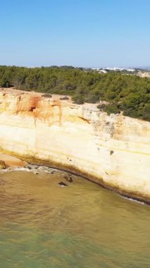 Dramatik kireçtaşı uçurumlarının manzarası ve Algar de Benagil 'de tenha bir plaj, Algarve, Portekiz, berrak mavi gökyüzü ve sakin deniz..