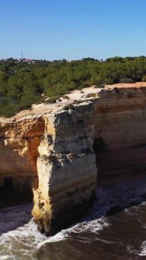 Algar de Benagil 'de, açık mavi gökyüzünün altında yemyeşil bir ormanın olduğu denizin üzerinde dik kireçtaşı kayalıklar yükselir. Engebeli kıyı şeridi ve mağara açılışı çarpıcı bir doğal manzara yaratır..