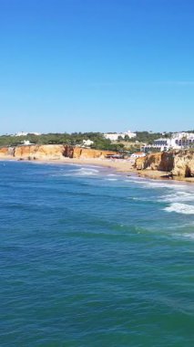 Albufeira yakınlarındaki Algarve sahil şeridinin manzarasında altın kayalıklar, kumlu sahil, turkuaz deniz ve açık mavi gökyüzü yer alıyor. Güney Portekiz 'de popüler tatil beldesi.