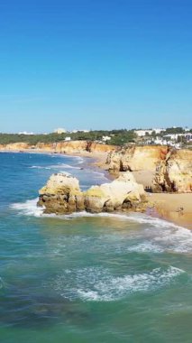 Güneşli bir günde Portekiz 'in Albufeira kenti yakınlarındaki Algarve sahili boyunca altın kayalıkların, turkuaz denizin ve kumlu plajların manzarası..