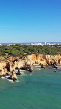Portekiz 'in Albufeira yakınlarındaki Algarve kıyı şeridi boyunca, parlak mavi gökyüzünün altında dramatik uçurumların ve berrak turkuaz suların manzarası..