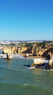 Portekiz 'in Albufeira yakınlarındaki Algarve kıyı şeridi boyunca turkuaz sularından dramatik altın uçurumlar ve deniz yığınları yükseliyor..