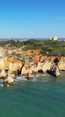 Portekiz 'in Albufeira kenti yakınlarındaki Algarve kıyısında, parlak mavi gökyüzünün altında dramatik kayalık kayalıklar ve berrak turkuaz sular..
