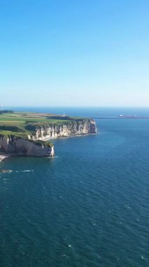 Etretat, Normandiya, Fransa 'da açık bir gökyüzü altında dramatik beyaz tebeşir uçurumları ve mavi deniz manzarası.