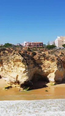 Albufeira, Algarve, Portekiz 'deki berrak mavi gökyüzünün altında modern binaların olduğu dramatik uçurumların ve kumlu plajların manzarası..