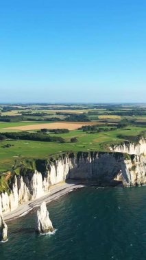 Etretat, Normandiya, Fransa kıyıları boyunca açık mavi gökyüzünün altında dramatik beyaz tebeşir ve turkuaz deniz manzarası.