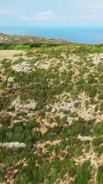 Col de la Serra 'da yakalanan, parçalı bulutlu gökyüzünün altında denize açılan yemyeşil dağların manzarası..
