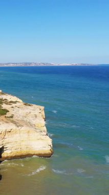 Portekiz 'in Algar de Benagil yakınlarındaki Algarve sahilinin berrak turkuaz sularını bulutsuz mavi gökyüzünün altında dramatik kireçtaşı kayalıkları gözden kaçırır..