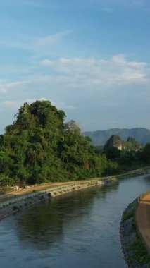Laos 'taki Nam Theun 2 yakınlarında, yemyeşil manzaralar ve dramatik kireçtaşı dağları arasında, bulutlu bir gökyüzünün altında sakin bir nehir akar..