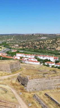 Portekiz, Elvas 'ta açık mavi bir gökyüzü altında küçük bir kasaba ve yuvarlanan tepelerle çevrili antik taş tahkimatlarının havadan görünüşü.