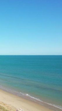 İtalya 'nın Isola Varano Doğa Rezervi' nde berrak mavi bir gökyüzü altında sakin bir kumsal ve durgun bir turkuaz deniz manzarası. Huzurlu kıyı manzarası rahatlama ve seyahat kavramları için mükemmeldir..