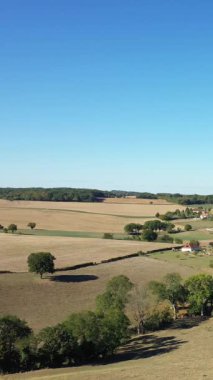 Yuvarlanan tarlalar, dağınık ağaçlar ve açık mavi gökyüzünün altındaki uzak çiftlik evleri Fransız kırsalında Cuncy les Varzy.