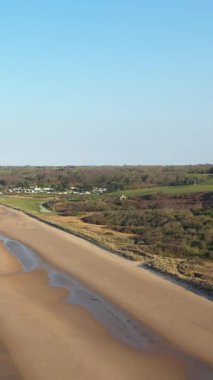 Fransa 'nın Normandiya kentinde, yumuşak dalgalar ve uzak kırsal bölgelerle Omaha Sahili' nin engin kumlu kıyı şeridinin havadan görüntüsü. Açık mavi gökyüzü ve huzurlu kıyı manzarası.