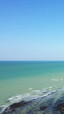 Turkuaz okyanus dalgalarının berrak mavi gökyüzü ile buluşması, Port en Bessin 'de yakalanır. Yumuşak sörf ve açık ufukta huzurlu bir deniz manzarası..