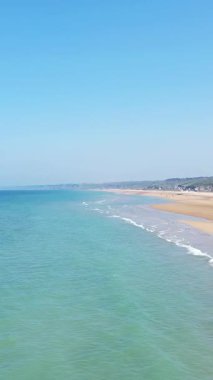 Parlak mavi gökyüzünün altında turkuaz su ve altın kumla Omaha Sahili manzarası, Normandiya, Fransa. Huzurlu deniz manzarası seyahat ve doğa kavramları için idealdir.
