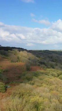 Parçalı bulutlu bir gökyüzünün altında Normandiya 'daki Omaha Sahili yakınlarındaki kayan kum tepelerinin ve kıyı manzarasının manzarası. Uzaktaki küçük köy binaları görülebilir..