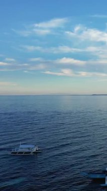 Açık mavi gökyüzünün altında sakin okyanus suları, yumuşak bulutlar, Filipinler, Panglao 'da ele geçirildi. Huzurlu deniz manzarası rahatlama ve seyahat temaları için ideal.