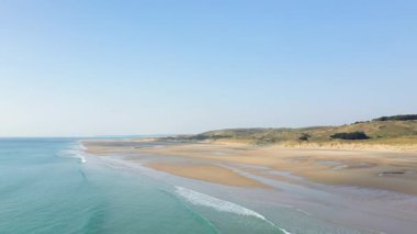 Geniş kumlu kıyı şeridinin havadan görünüşü ve Plage de la Vieille 'deki yumuşak dalgalar berrak mavi gökyüzünün altında..