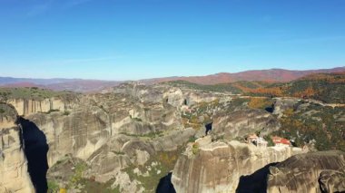Yunanistan 'ın Thessaly kentindeki tarihi uçurumların tepesinde, açık mavi bir gökyüzünün altında, dramatik Meteora kaya oluşumlarının havadan görünüşü.