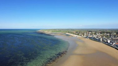 Açık bir günde kumlu sahil ve kıyı köyü Grandcamp Maisy, Normandiya, Fransa 'nın insansız hava aracı görüntüleri. Görüntü kıyı şeridini, turkuaz denizi ve büyüleyici sahil kasabasını yakalıyor..