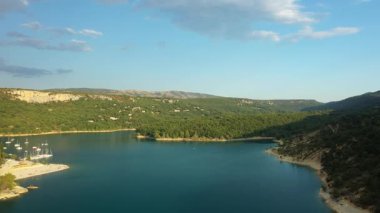 Sainte Croix Gölü 'nün sakin manzarası. Mavi gökyüzünün altındaki yemyeşil tepelerle çevrili turkuaz su. Provence, Fransa 'da Yakalandı.