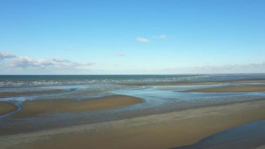 Normandiya, Fransa 'daki Utah Sahili' nin geniş manzarası açık mavi gökyüzünün altında kumsallar ve sığ sular gösteriyor..