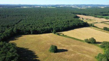 Drone shot of open fields, forests, and rolling hills in the Morvan countryside on a clear summer day.