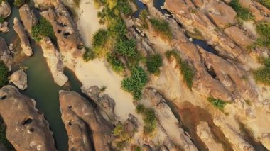 Champassak, Laos 'taki Mekong Nehri boyunca yeşil bitki örtüsü ve berrak mavi sularla kayalık oluşumların ve kumsalların insansız hava aracı görüntüsü..