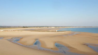 Plage de la Potiniere 'de gelgit havuzları ve durgun mavi suyu olan geniş kumlu sahil, berrak bir gökyüzünün altında. Huzurlu kıyı manzarası rahatlama ve doğa geçmişi için ideal..