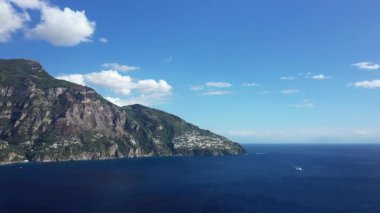 Güneşli bir günde, Positano kıyı şeridi boyunca engebeli uçurumların ve derin mavi denizin nefes kesici manzarası..