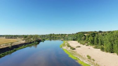 Loire nehrinin kumlu kıyıları ve açık mavi bir gökyüzünün altında Imphy, Fransa yakınlarındaki yemyeşil ağaçları olan hava manzarası. Huzurlu kırsal alan doğa ve seyahat temaları için ideal.