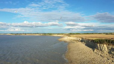 Fransa 'nın La Rochelle yakınlarındaki mavi gökyüzünün altındaki kayalık kıyı şeridi ve uçurumların manzarası. Sakin deniz ve dramatik bulutlar sakin bir kıyı manzarası yaratır..