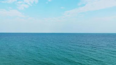 Mavi okyanusun sakin manzarası Coconut Plajı 'nda yumuşak bulutların altında gökyüzü ile buluşuyor. Huzurlu deniz manzarası arka plan veya rahatlama kavramları için idealdir.