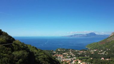 Scenic view of Maratea coastline with turquoise sea, lush green hills, and a dramatic mountain under a clear blue sky. Picturesque Italian village nestled along the Mediterranean shore.
