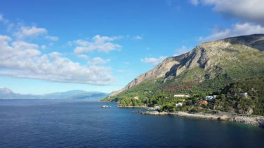 Scenic view of the Maratea coastline with clear blue sea, rugged mountains, and scattered houses under a bright sky. Captured near Porto in southern Italy.