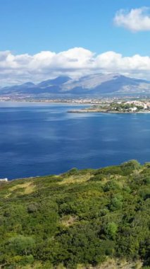 Isola di Cirella 'daki açık mavi deniz ve uzak dağlarla dolu yemyeşil bitki örtüsünün insansız hava aracı görüntüleri, Calabria, İtalya. Canlı kıyı manzarası seyahat ve doğa kavramları için idealdir..