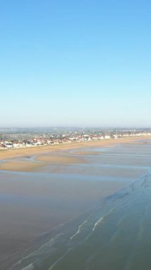Geniş kumlu sahil alçak gelgitte Lion-sur-Mer kasabası açık mavi gökyüzü altında, Kılıç Sahili, Normandiya, Fransa.