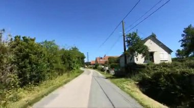 Fransa 'nın Morvan bölgesinde güneşli kırsal yol kavşağı, yemyeşil ve açık mavi gökyüzünün altında geleneksel bir evle sınırlıdır..