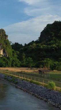 Laos 'taki Nam Theun 2 yakınlarında akan bir nehir ve yeşil manzaranın yanında yemyeşil kireçtaşı karst manzarası. Mavi gökyüzünün altında sakin bir doğal ortam..