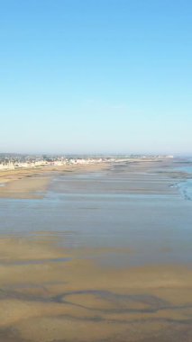 Lion-sur-Mer, Normandiya 'daki Sword Beach' in sakin suları ve berrak mavi gökyüzü geniş bir görüş alanına sahip. Kıyı kasabası binaları kıyı şeridi boyunca görülebiliyor..