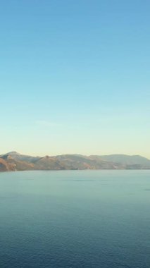 Sakin mavi sularla sakin deniz manzarası ve berrak bir gökyüzü altında uzak dağlar, İtalya Capitello yakınlarında ele geçirildi..