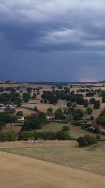 Fransa 'nın Varzy şehrinde çarpıcı ve fırtınalı bir gökyüzü altında dağınık ağaçlar ve çiftlik evleri olan geniş kırsal alan..