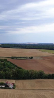 Fransa 'nın Cuncy les Varzy kırsalında bulutlu bir gökyüzü altında ekili tarlaların ve çitlerin geniş bir manzarası. Tarımsal arazisi ve uzak ağaç çizgileri olan huzurlu kırsal manzara.