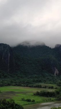 Vang Vieng, Laos yakınlarındaki sis kaplı dağların altına uzanan yemyeşil pirinç tarlaları huzurlu bir kırsal alan oluşturuyor..